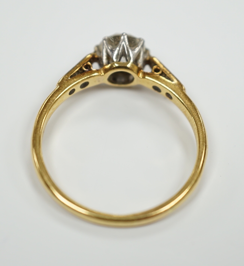An 18ct, plat. and single stone diamond ring, with diamond set shoulders, the central stone measuring 6mm in diameter.